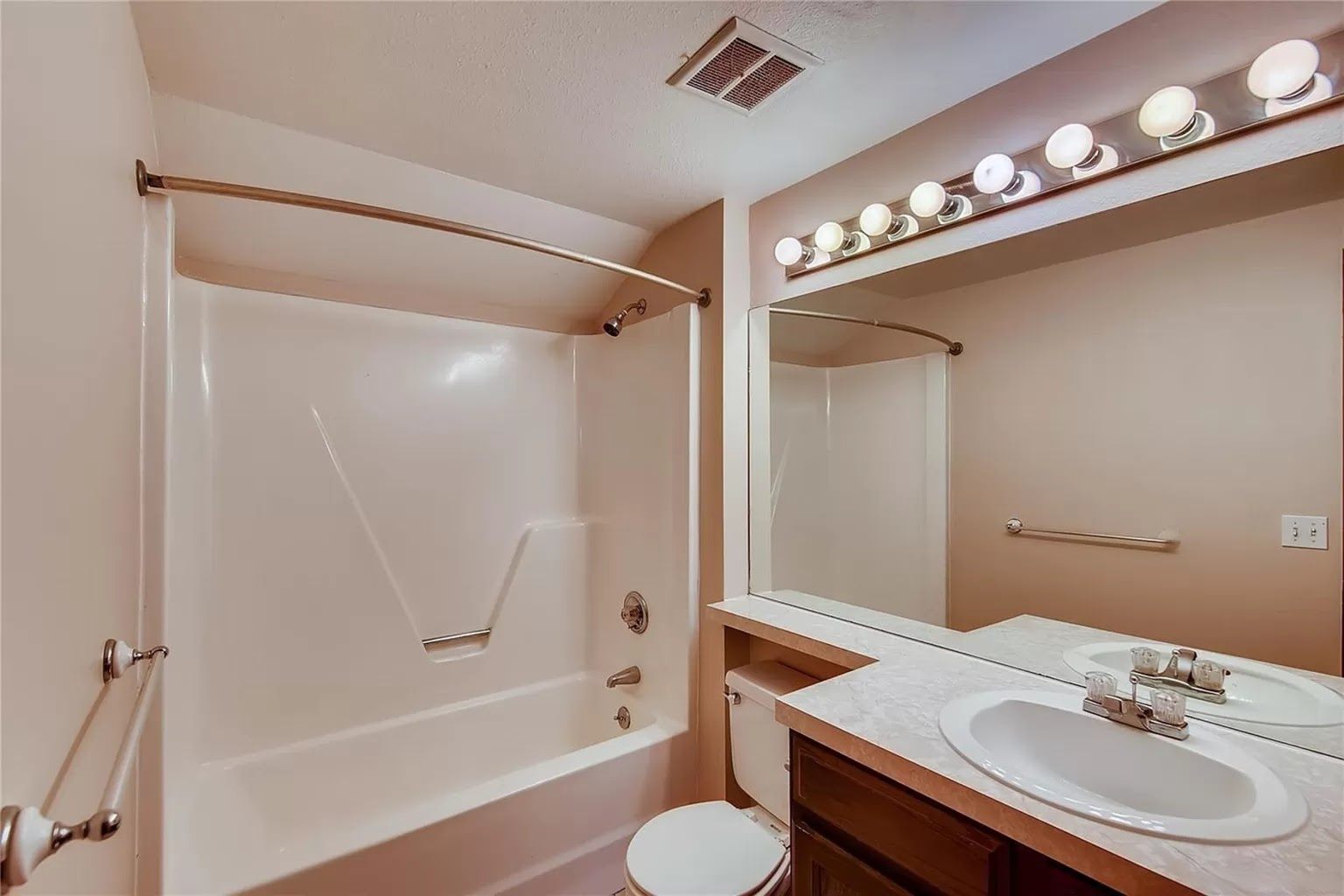Upstairs bathroom before remodeling: one-piece fiberglass tub and shower surround with a curtain rod and beige walls.